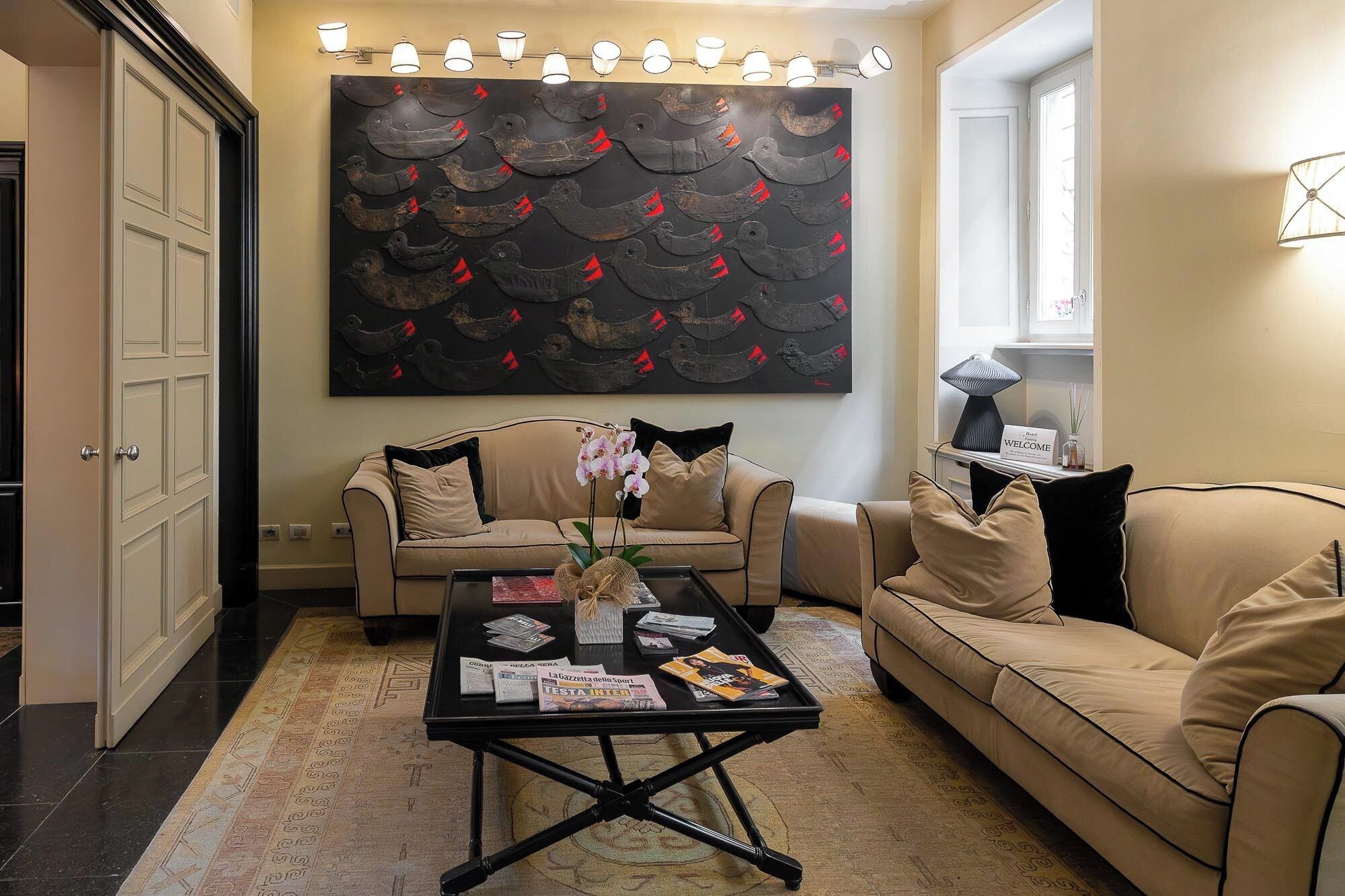 Una sala de estar con dos sofás color beige, una mesa de centro con revistas y un cuadro abstracto de gran tamaño en la pared.