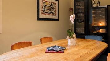Una mesa de madera para comer con libros, un florero con flores y una obra de arte abstracto enmarcada en la pared.