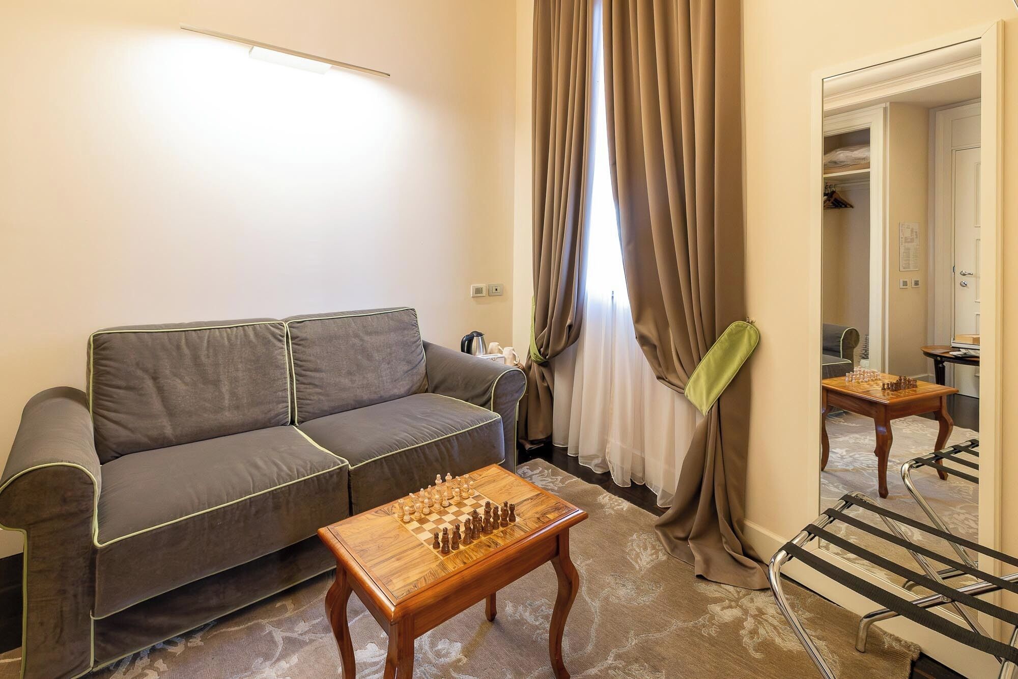 A living room with a sofa, a wooden chess table, and a mirror.