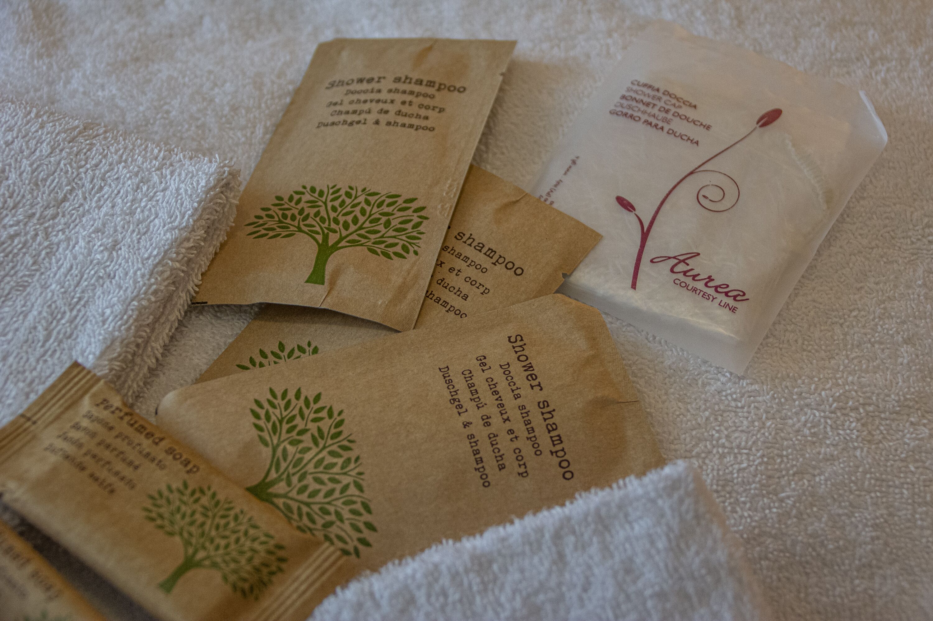 Plusieurs emballages de shampoing pour la douche et de savon parfumé sont posés sur une serviette blanche.