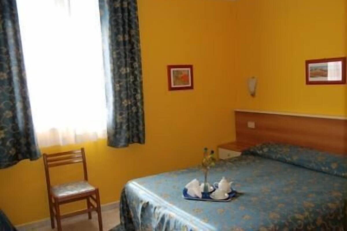 A room with a bed, a chair, and a nightstand.
