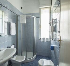 A bathroom with a glass-enclosed shower, a sink, and a toilet.