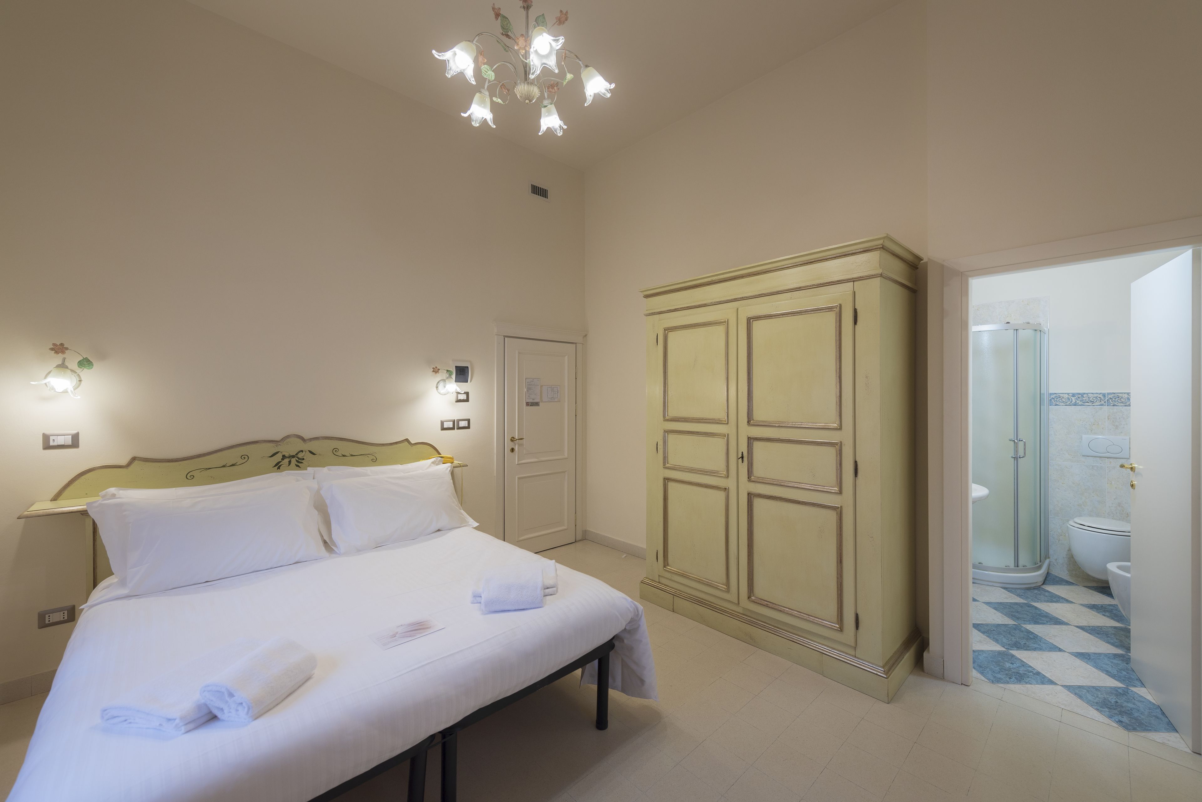 Una camera da letto con un letto, un armadio e un bagno visibile attraverso una porta aperta.