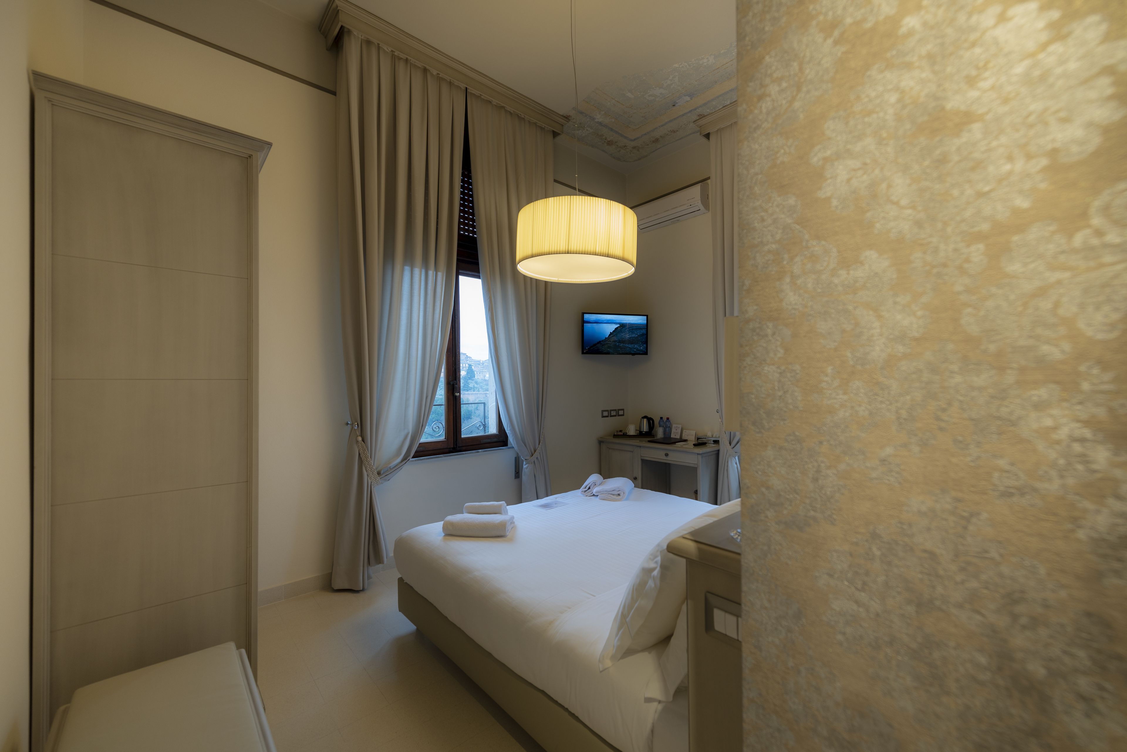 Une chambre d’hôtel avec un lit, une télévision et une table de chevet.