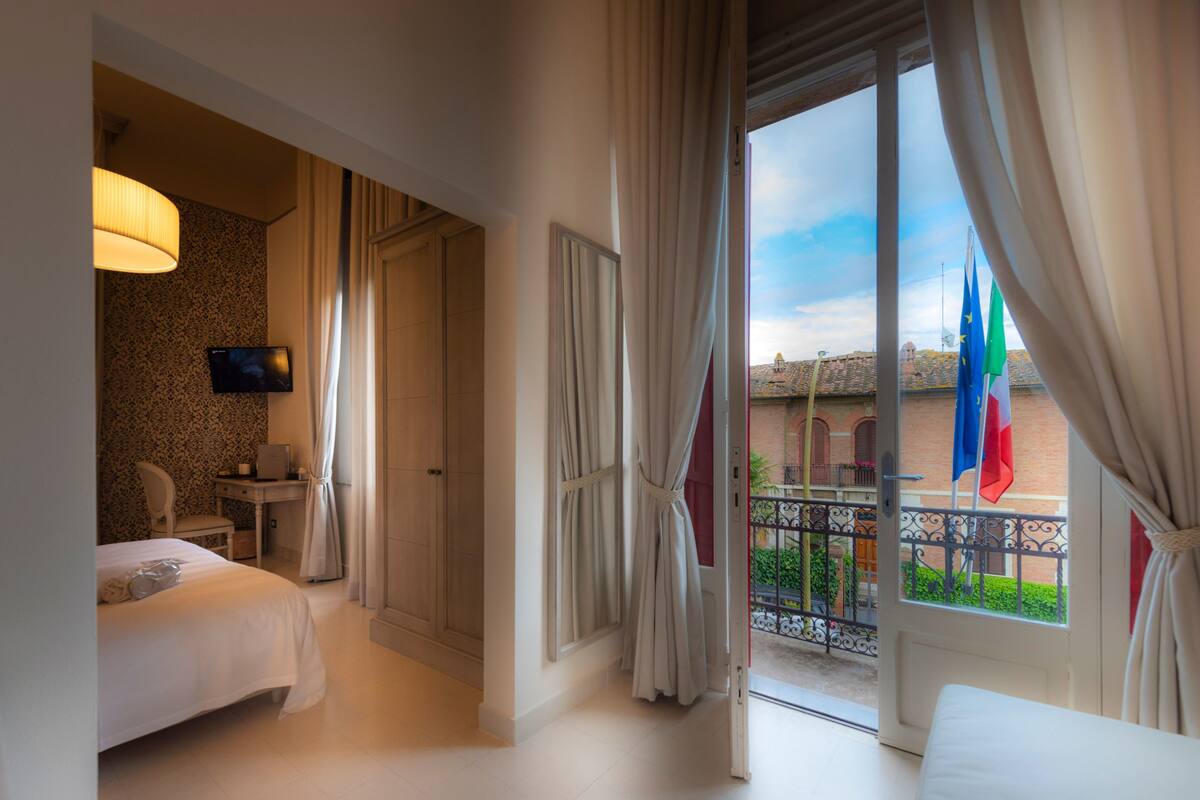 Une chambre d’hôtel avec deux lits, une télévision, un bureau et un balcon décoré de drapeaux.