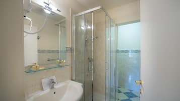 A bathroom with a glass-enclosed shower, a white sink, and a mirror above the sink.
