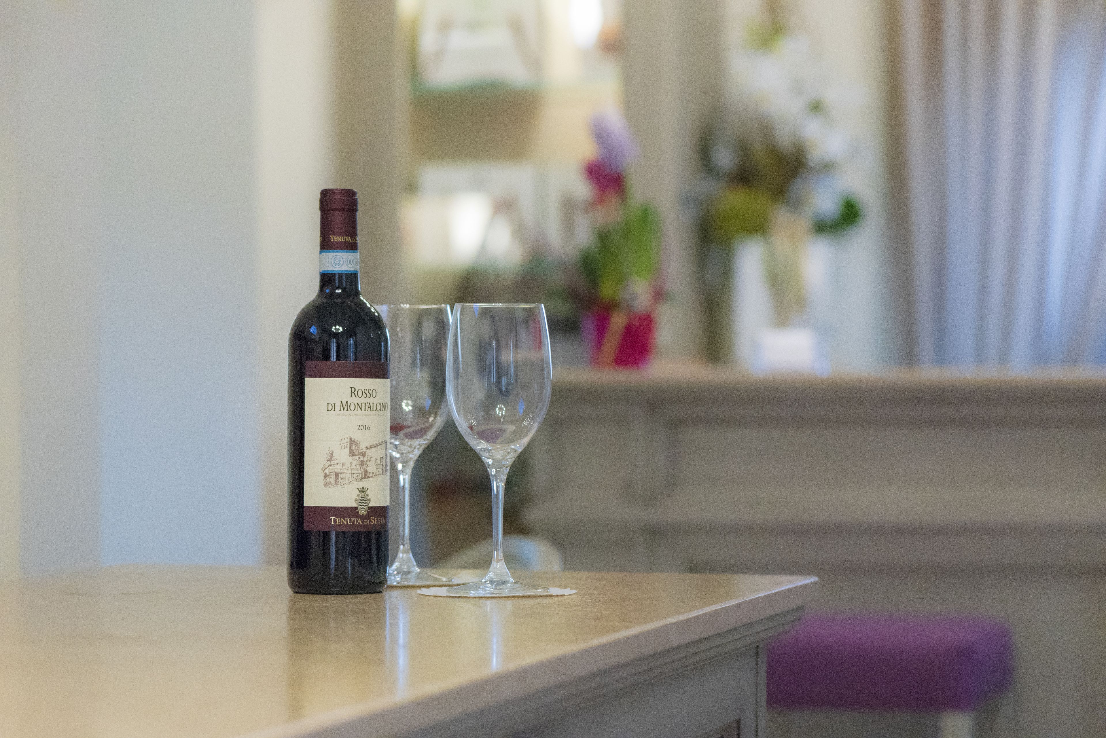 Uma garrafa de vinho rosé e dois copos em uma bancada.