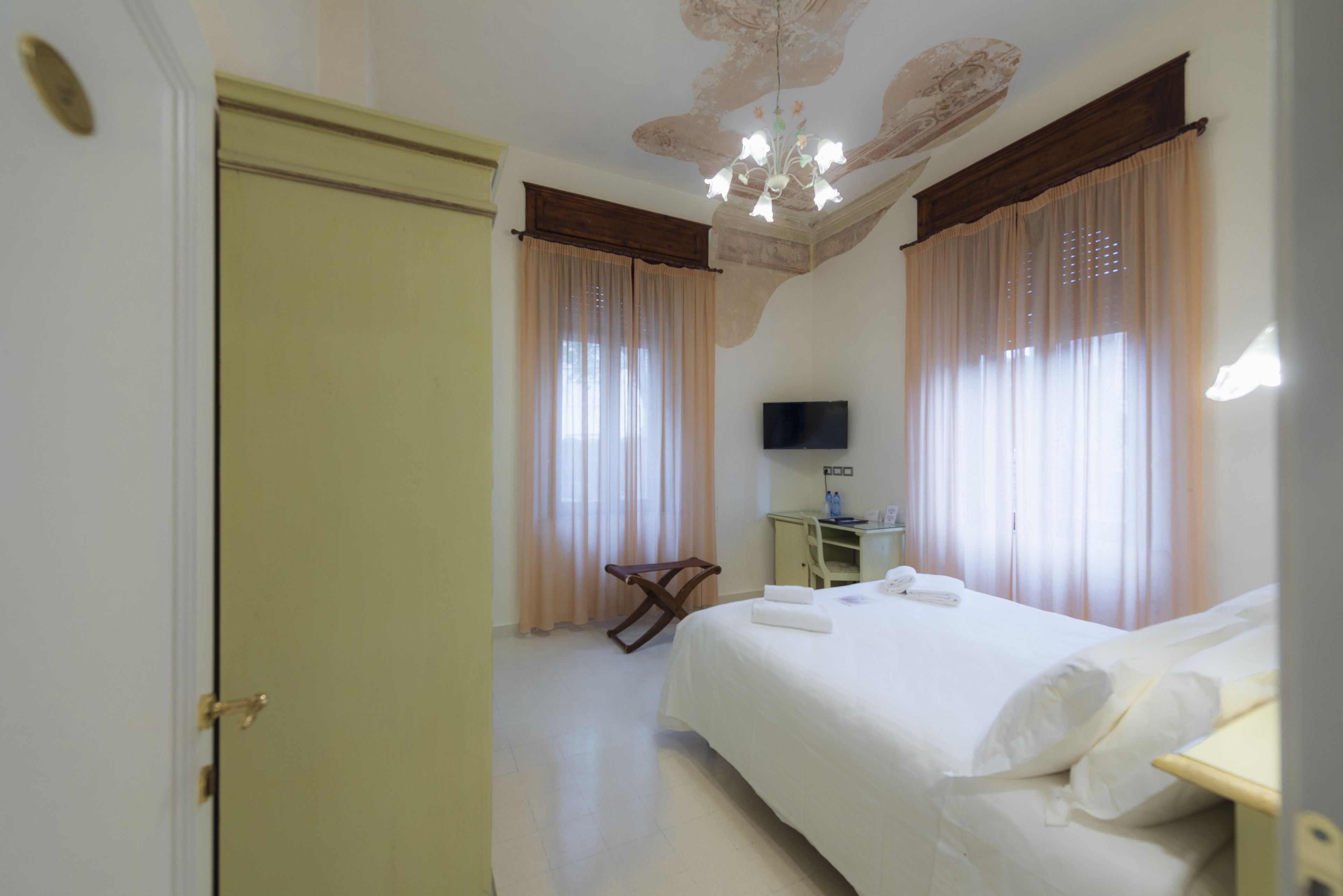 Una habitación de hotel con una cama, un escritorio, una silla, un televisor y una puerta.