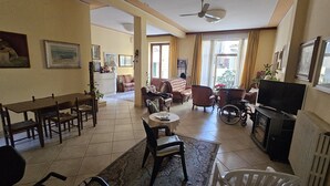 A spacious living room with a dining area, a television, and a wheelchair. - Verena (Montecatini Terme)