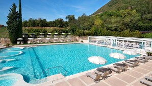 A swimming pool with sun loungers and umbrellas, surrounded by greenery and hills. - Verena (Montecatini Terme)