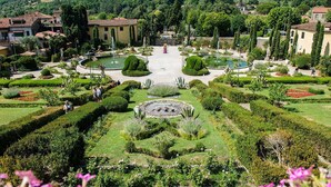 A formal garden with geometric hedges, a central fountain, and classical statues. - Verena (Montecatini Terme)