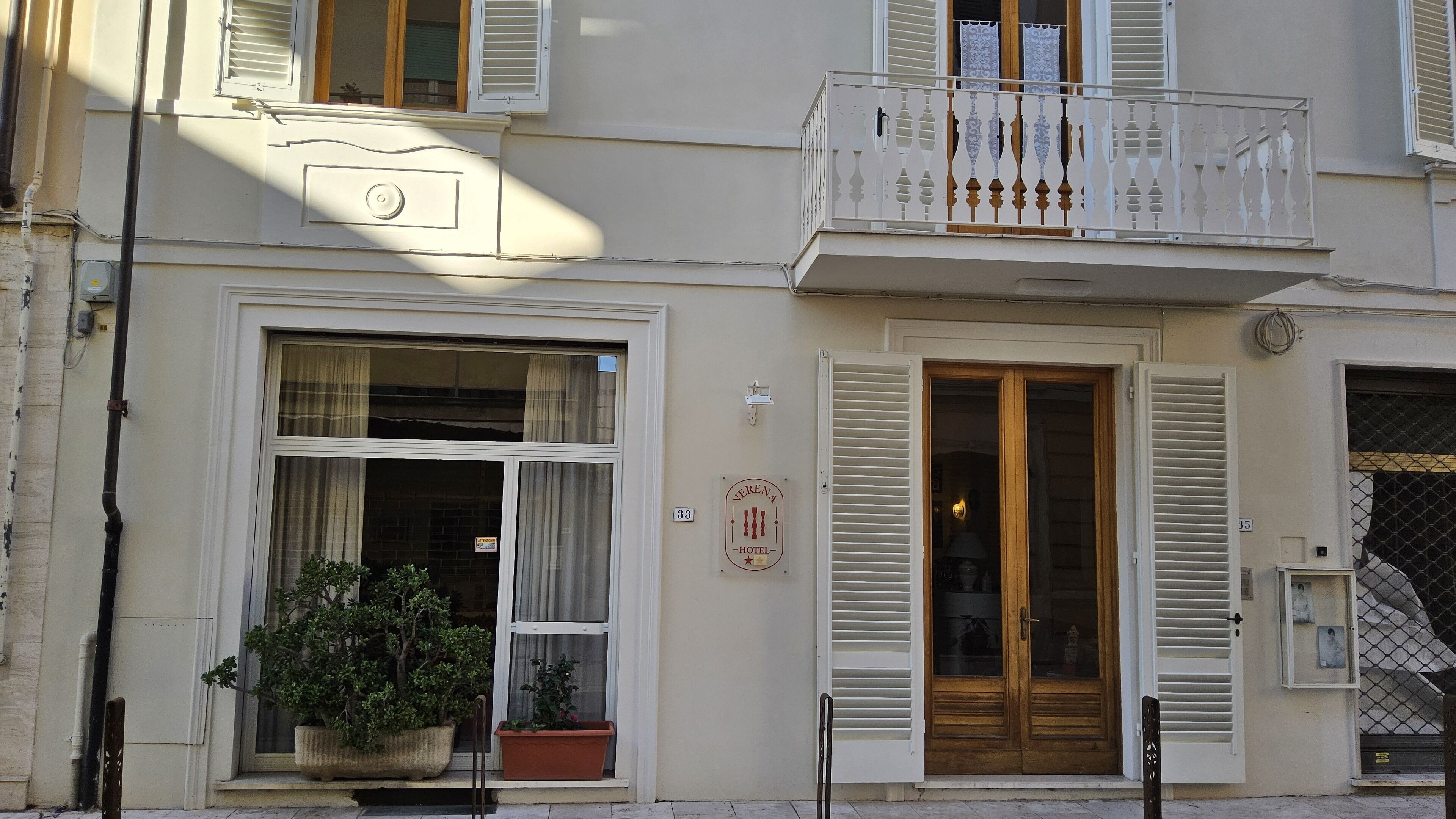 Ein Hotel mit Fassade, Balkon, großen Fenstern und einem Hinweisschild.