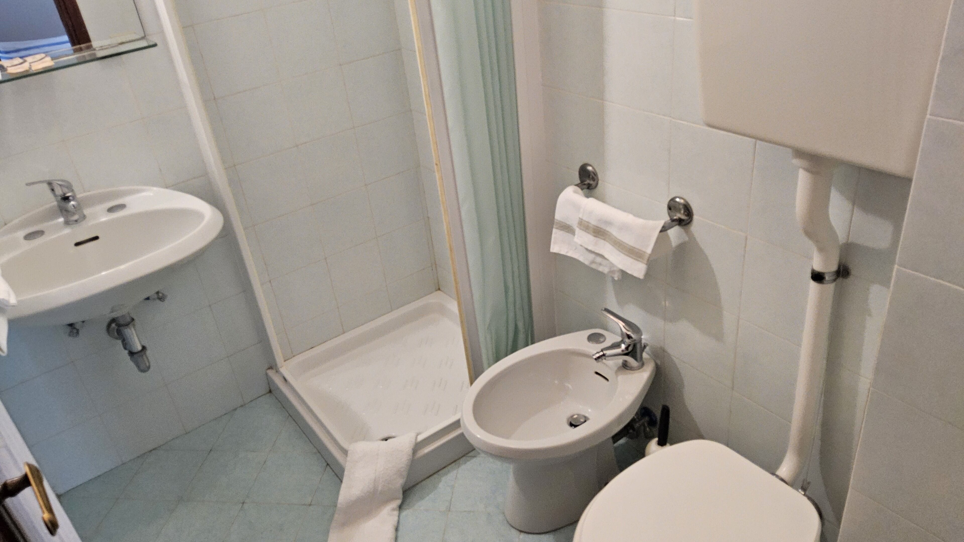 A small bathroom with a sink, a bidet, and a toilet.