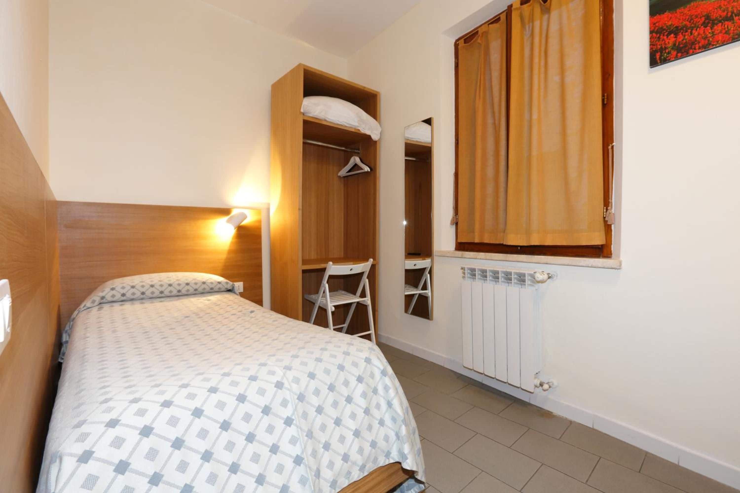 A bedroom with a bed, a wardrobe, a chair, and a radiator.