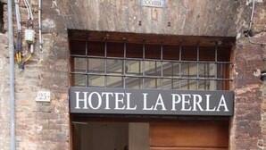 Entrada de un hotel con un cartel que dice 'HOTEL LA PERLA'.