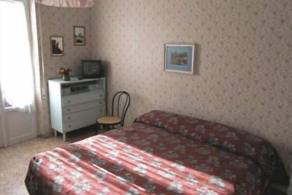 A bedroom with a bed, a dresser, a chair, and two framed pictures on the wall.