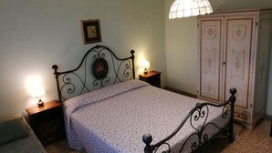 A bedroom with a bed, two bedside lamps, a nightstand, a wardrobe, and a hanging light fixture. - Roma (Rome)