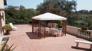 A covered outdoor seating area with a table and chairs, surrounded by a tiled patio. - Roma (Rome)