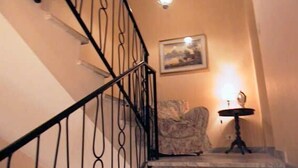 A staircase with a black railing, a small table with a lamp, and a framed picture on the wall. - Roma (Rome)