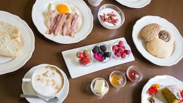 A breakfast setting with various dishes including toast, eggs, bacon, berries, and pastries.