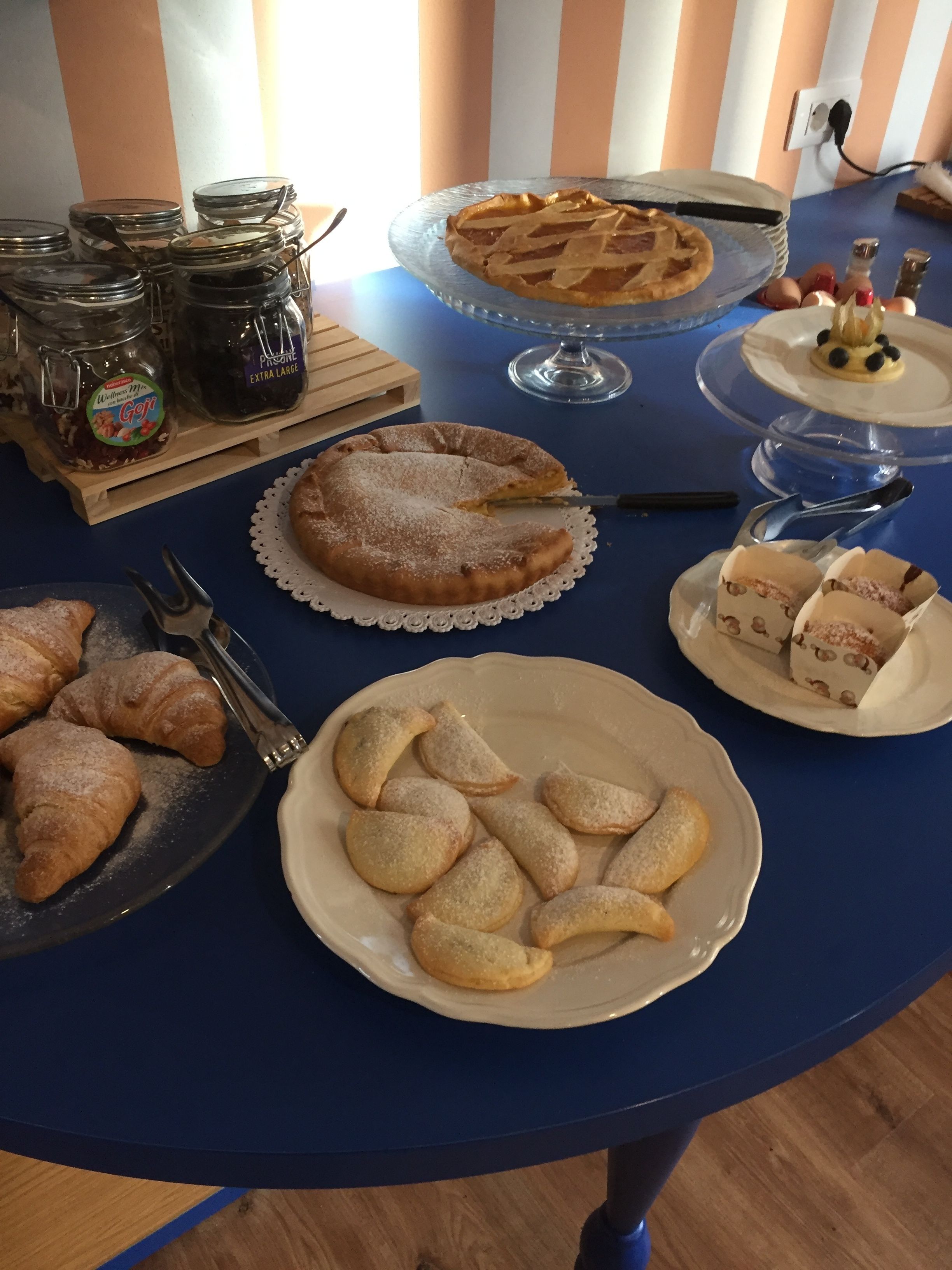 Ein Tisch mit verschiedenen Desserts, darunter ein Kuchen, Croissants und Gebäck, sowie Gläser mit Marmelade.
