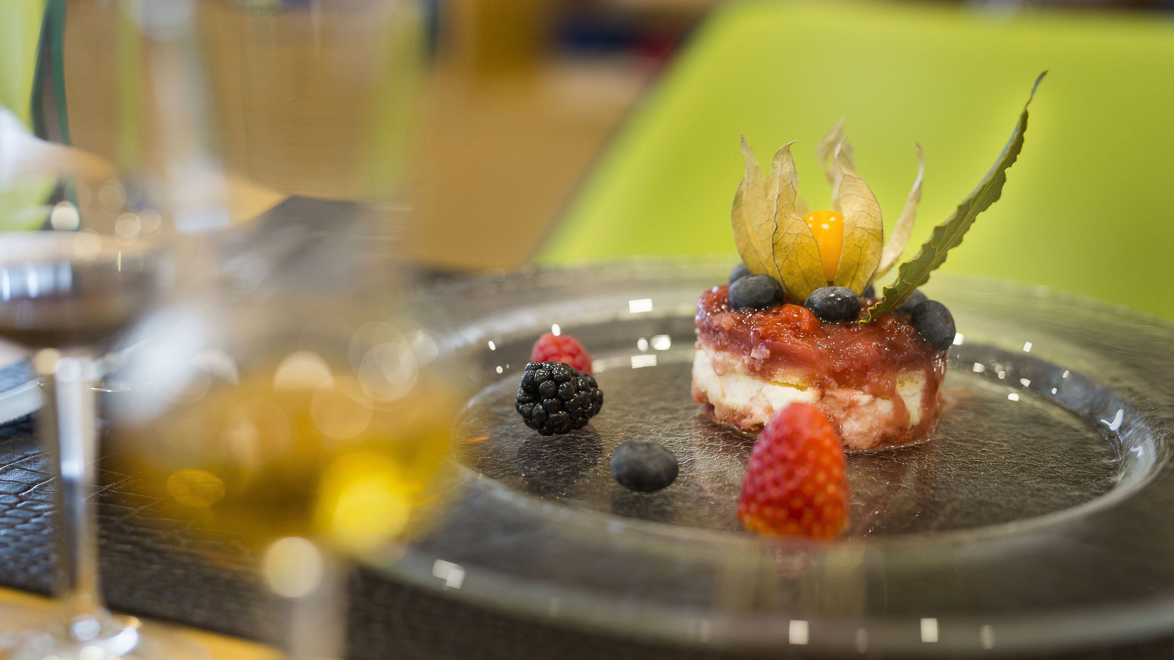 A dessert on a plate with berries and a glass of wine.