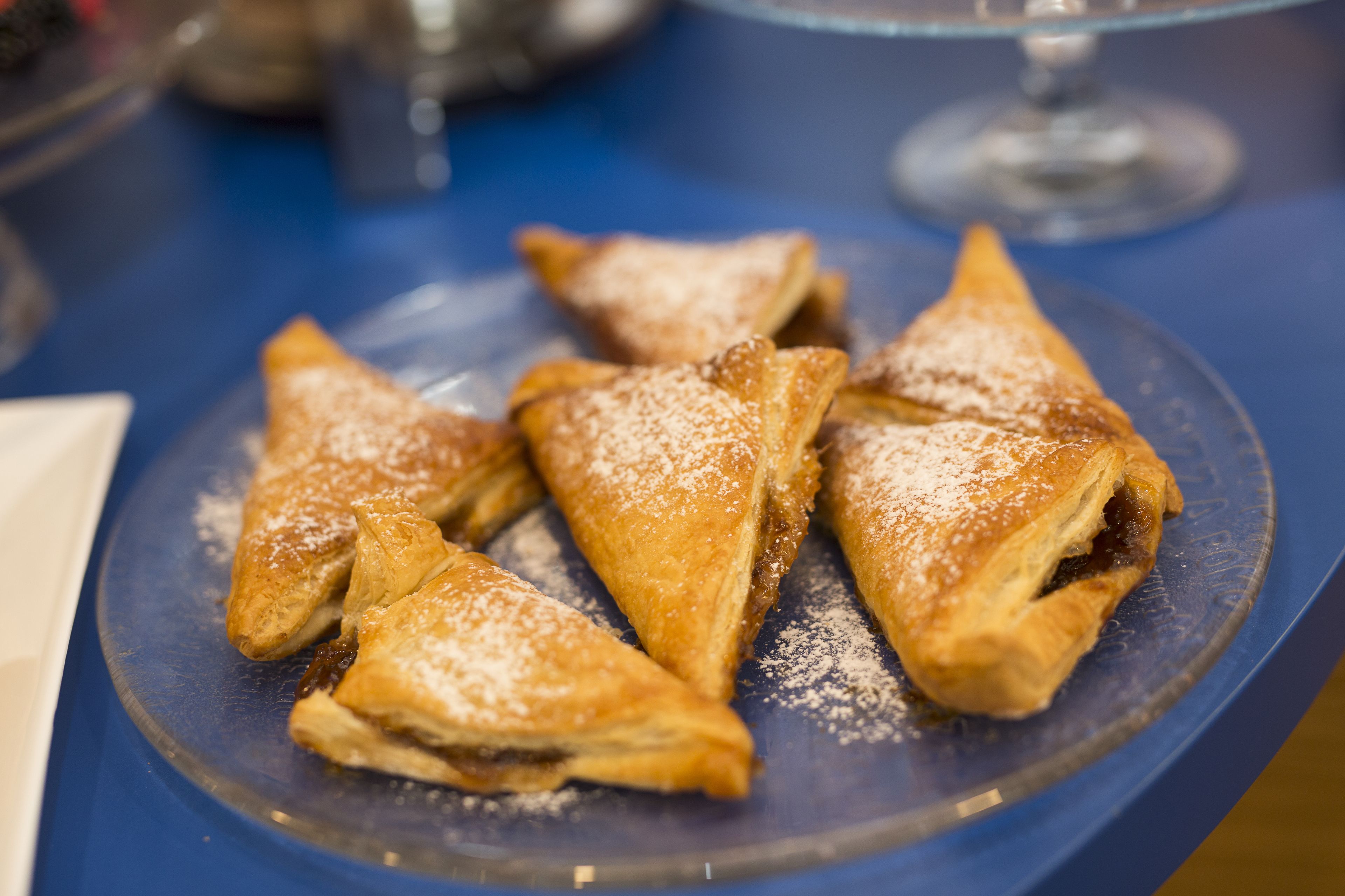 A plate of triangular pastries dusted with powdered sugar.