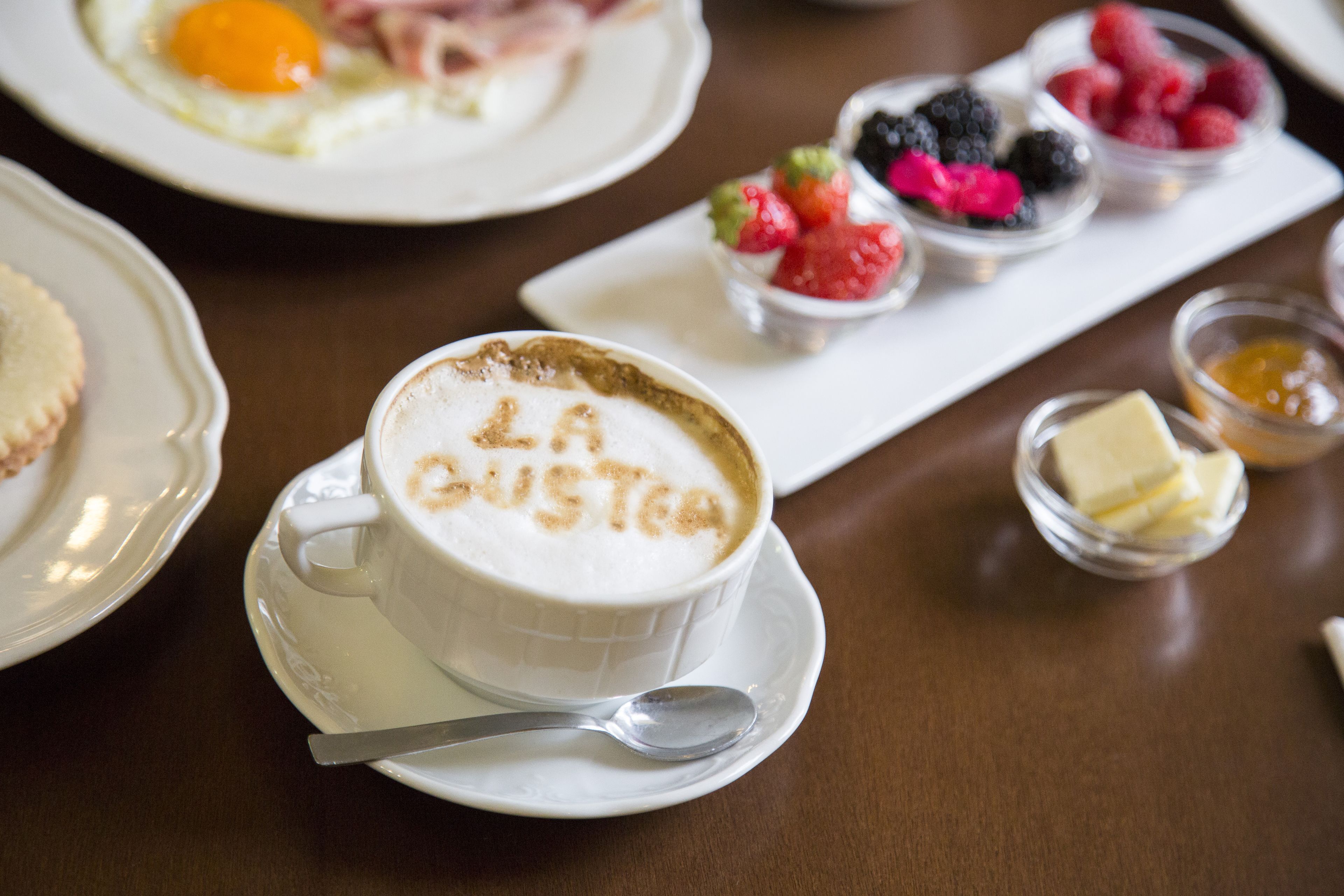 A breakfast setting with a cup of coffee and a plate of assorted berries.