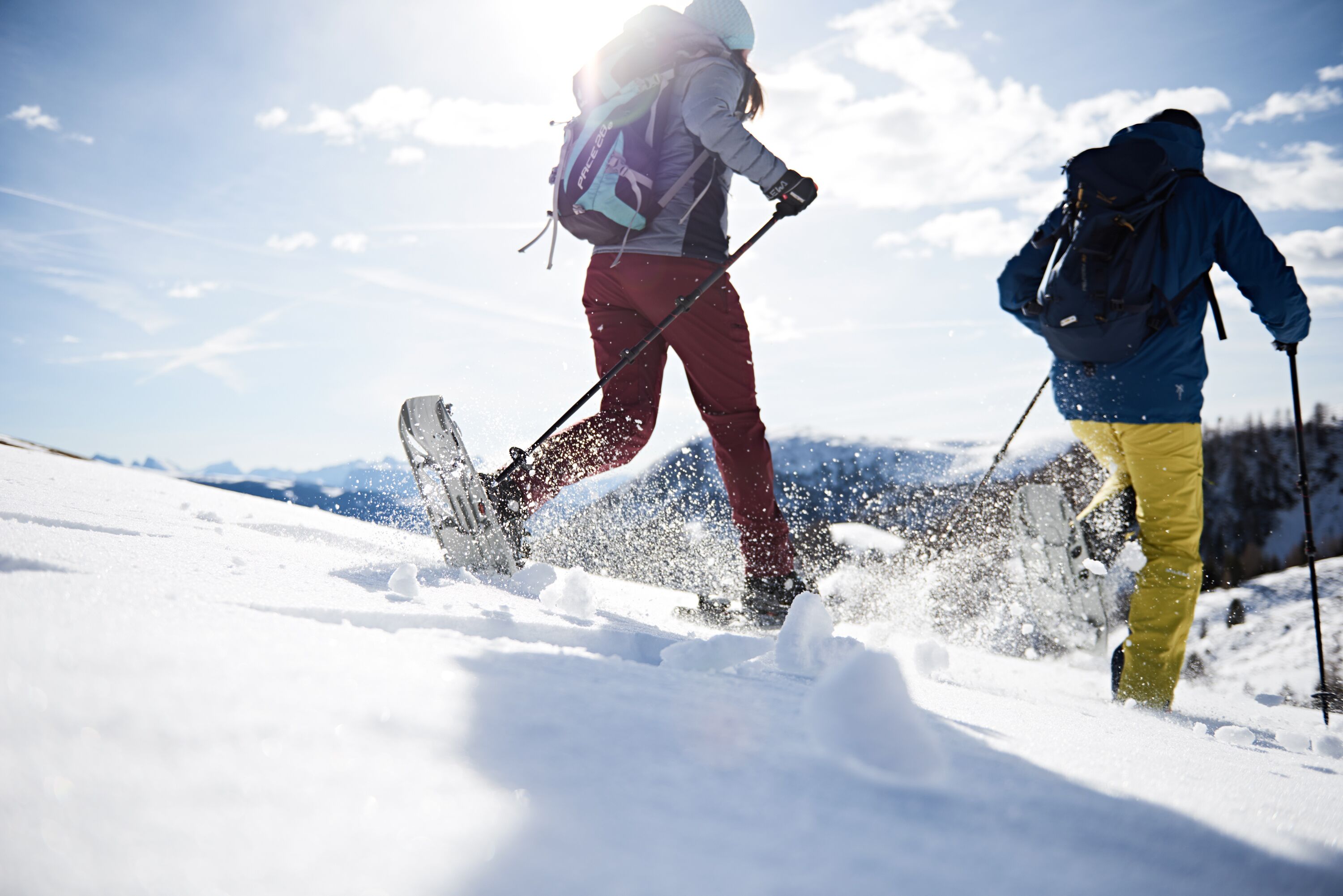 Two skiers in motion on a snowy slope with a clear sky.