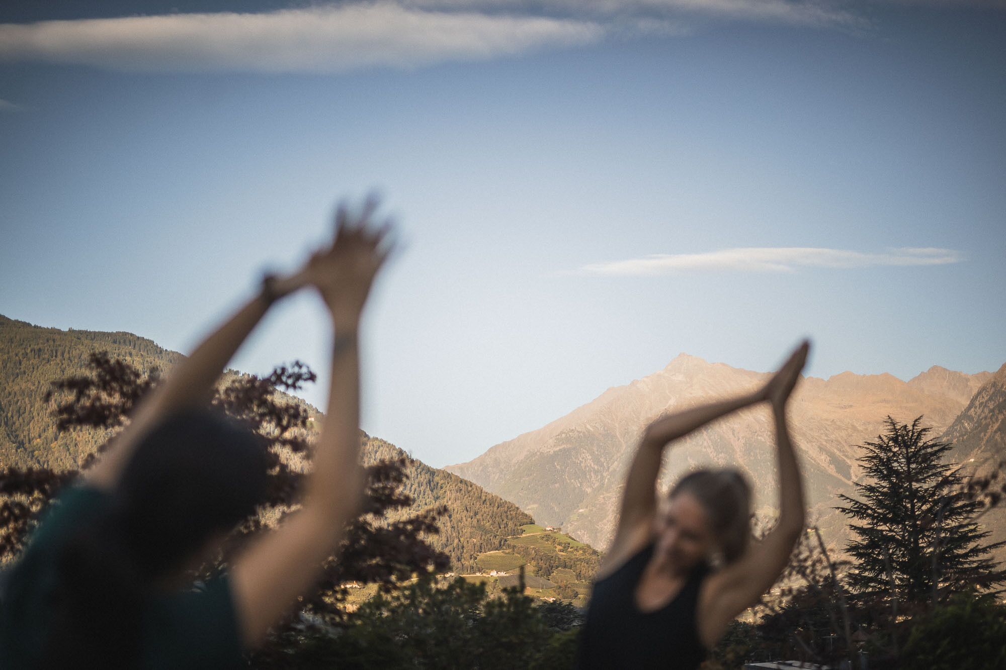 A mountainous landscape with two individuals performing yoga.