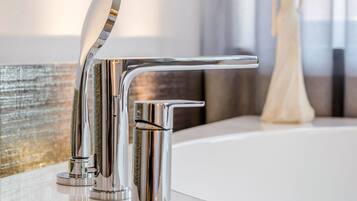 Ein modernes Badezimmer mit chromfarbenem Wasserhahn, einer Badewanne und einer dekorativen Vase.