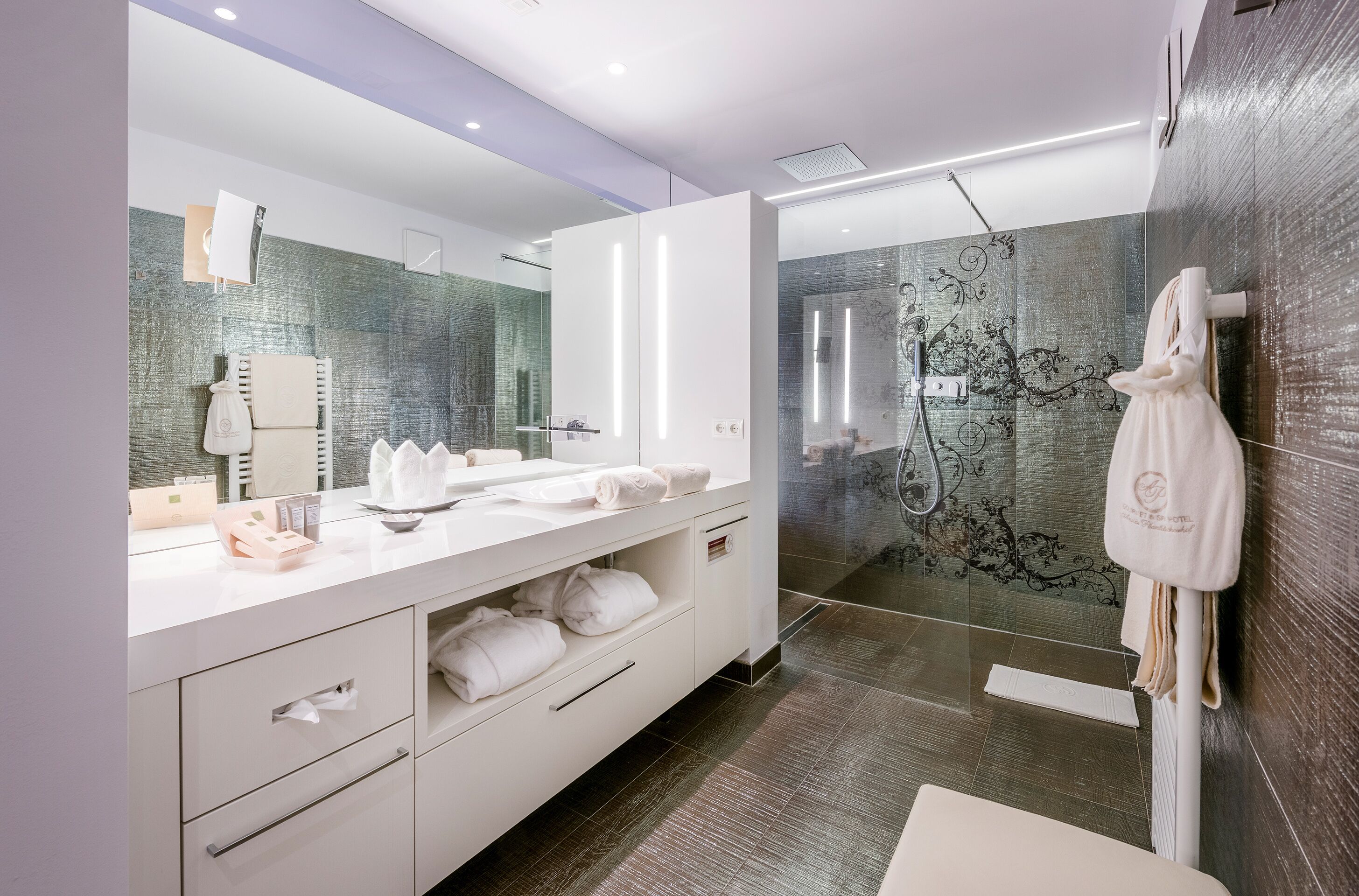 A modern bathroom with a large mirror, white vanity, and a glass shower enclosure.