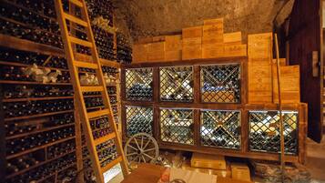 Une cave à vin avec des étagères en bois et une roue, ainsi que des caisses en bois empilées contre le mur.