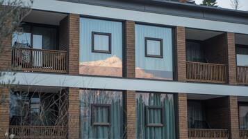 A modern multi-story building with balconies, large windows, and a mountain view.