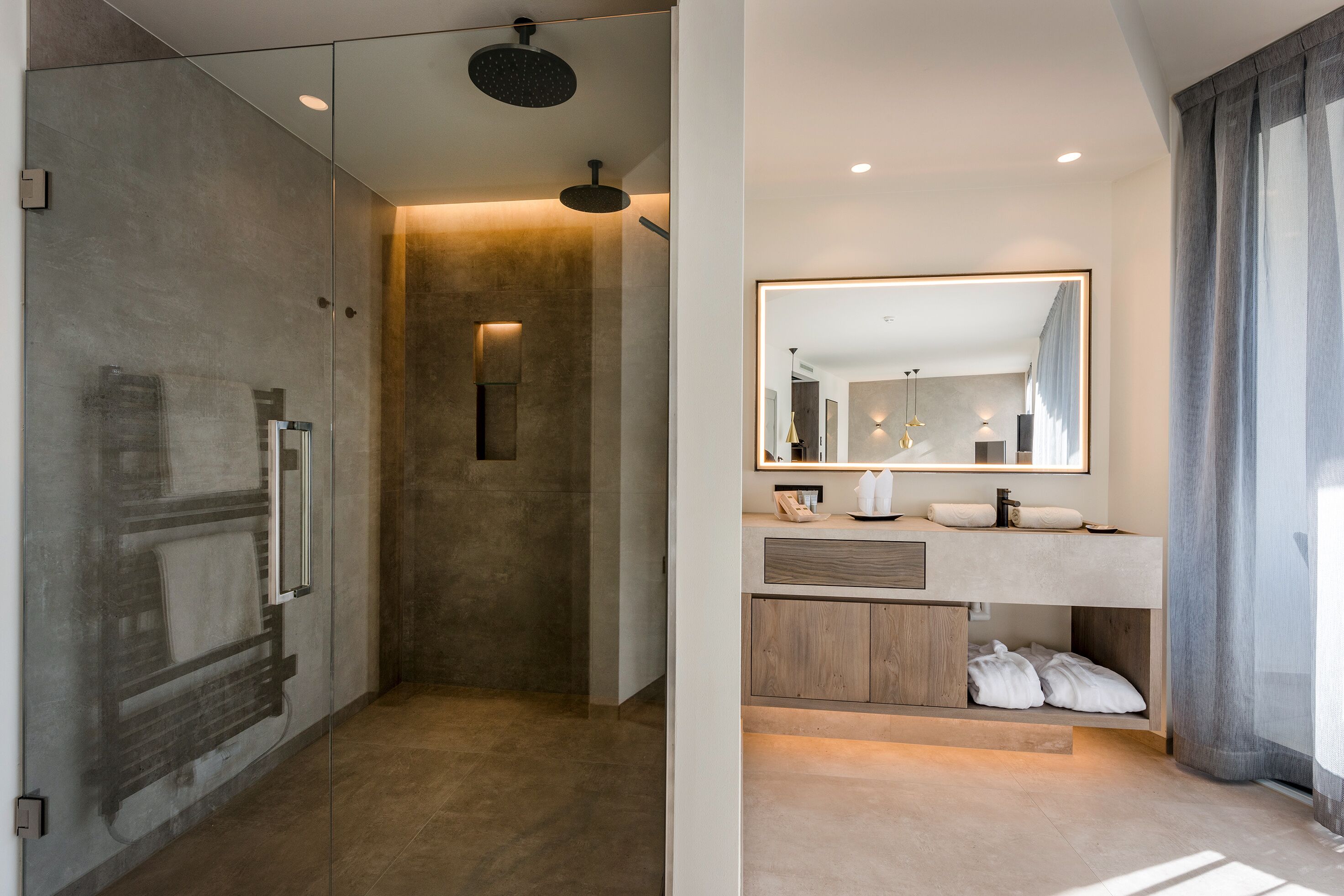 A modern bathroom with a glass shower enclosure, a vanity with a mirror, and a built-in cabinet.