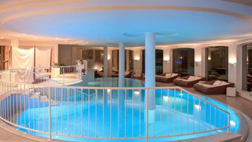 Una piscina techada, una piscina al aire libre, sombrillas