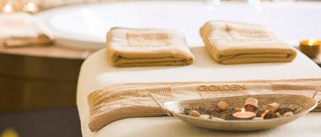 A spa setting with towels and a bowl of bath salts on a table.