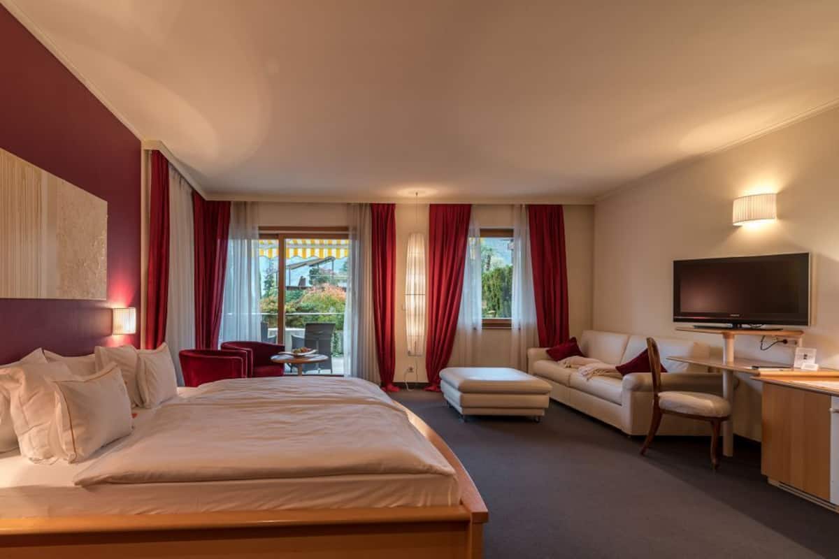 A hotel room with a large bed, a sofa, a TV, and a desk.