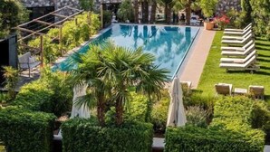 Ein Poolbereich mit Bergblick, umgeben von gepflegter Bepflanzung und modernen Gebäuden.