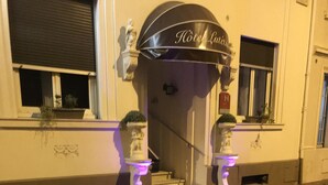 A hotel entrance with a sign reading "Hotel Lutetia" and two illuminated statues on the sidewalk. - Hotel Lutetia (Cannes)