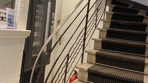 A staircase with a metal railing, carpeted steps, and a fireplace with a white mantel. - Hotel Lutetia (Cannes)
