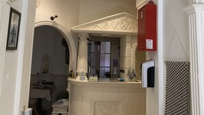A kitchen with a white archway, a red fire extinguisher, and a patterned towel. - Hotel Lutetia (Cannes)