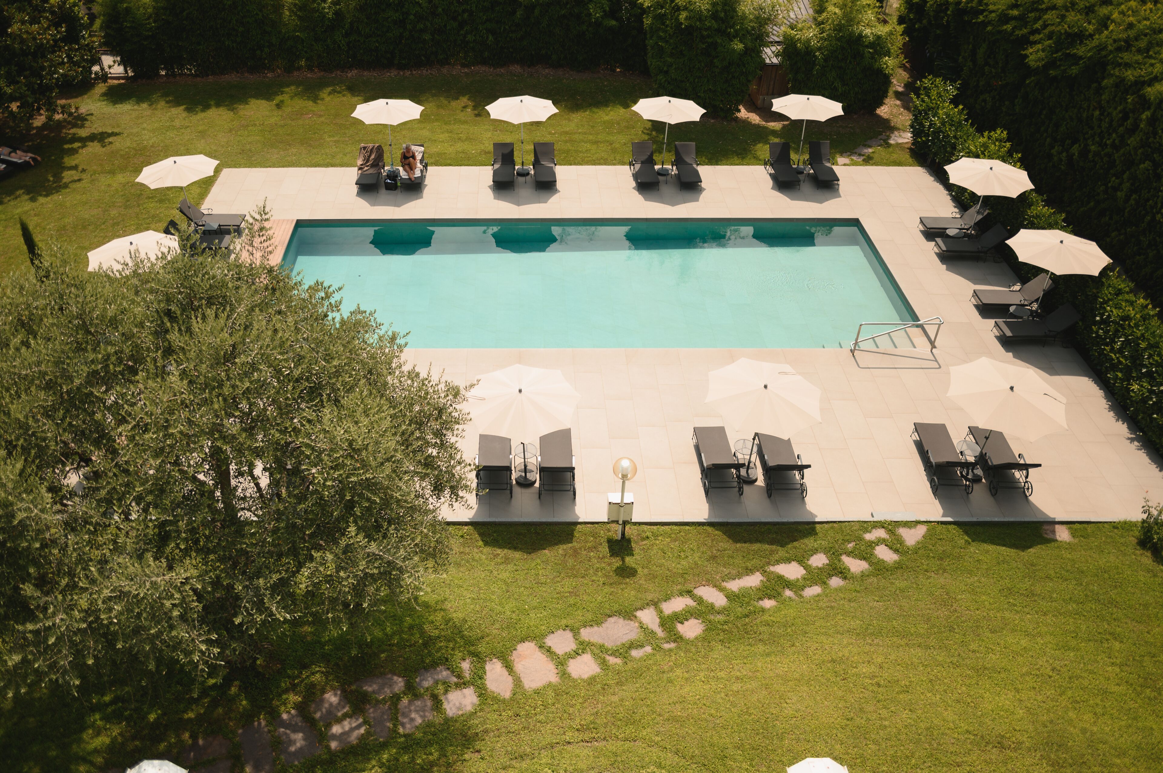 A rectangular pool with lounge chairs and umbrellas around it.