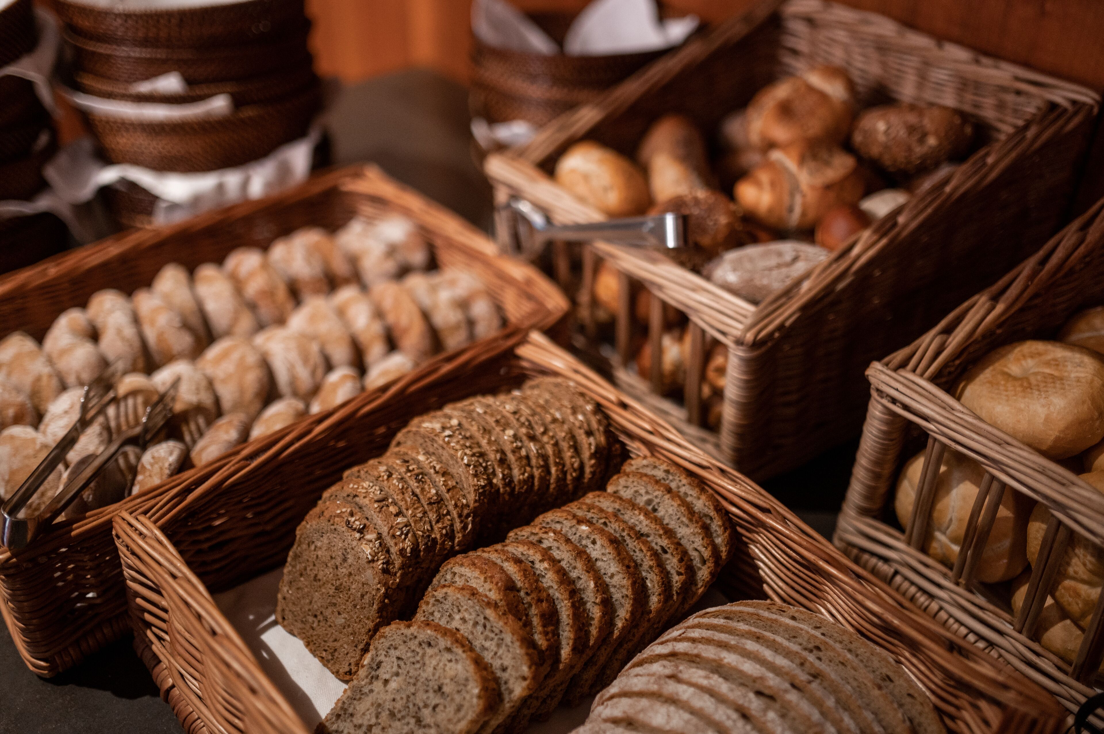 A variety of breads and pastries displayed in wicker baskets.