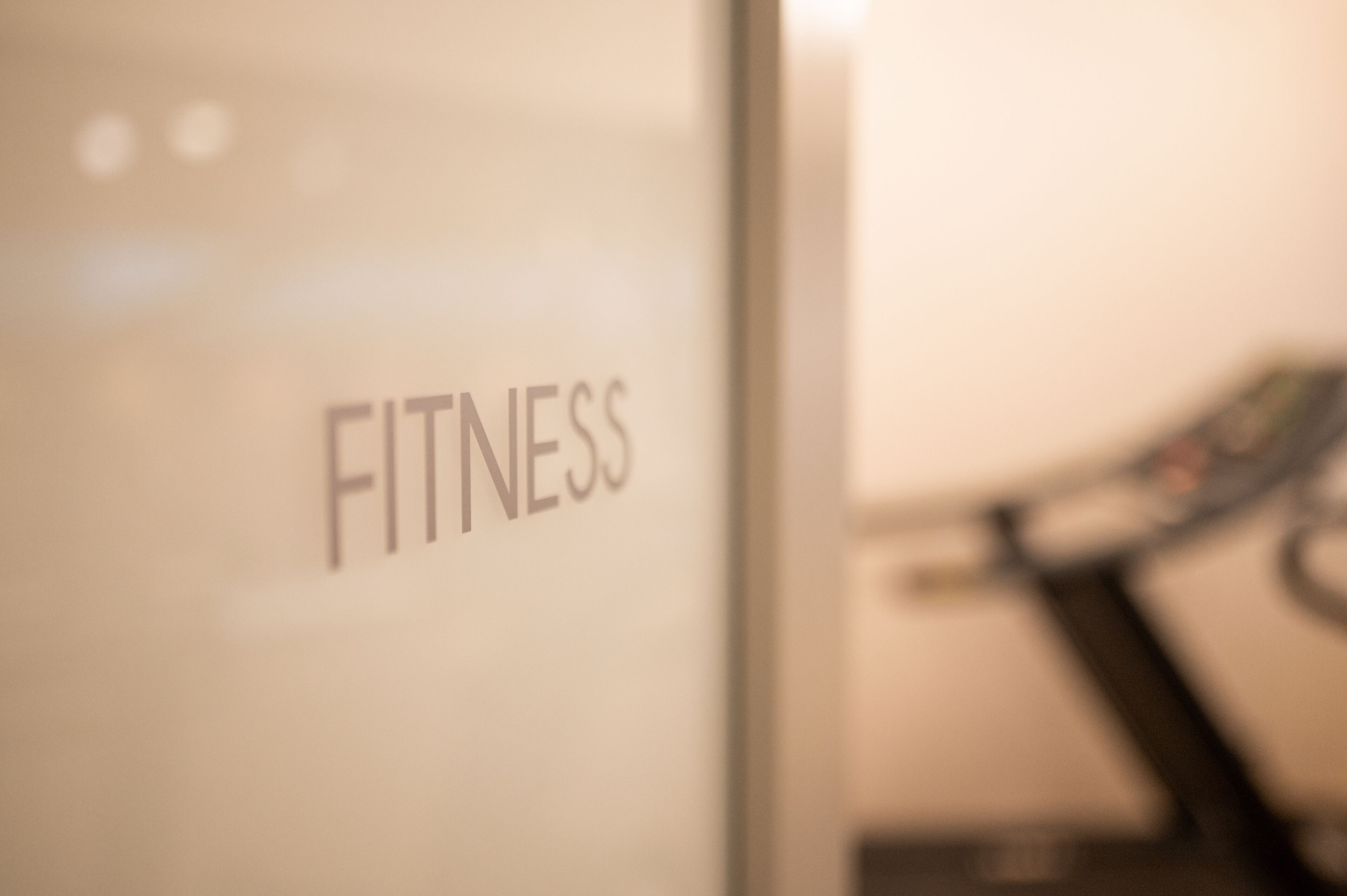 Un espace intérieur flou, avec une enseigne sur laquelle on peut lire « FITNESS ».