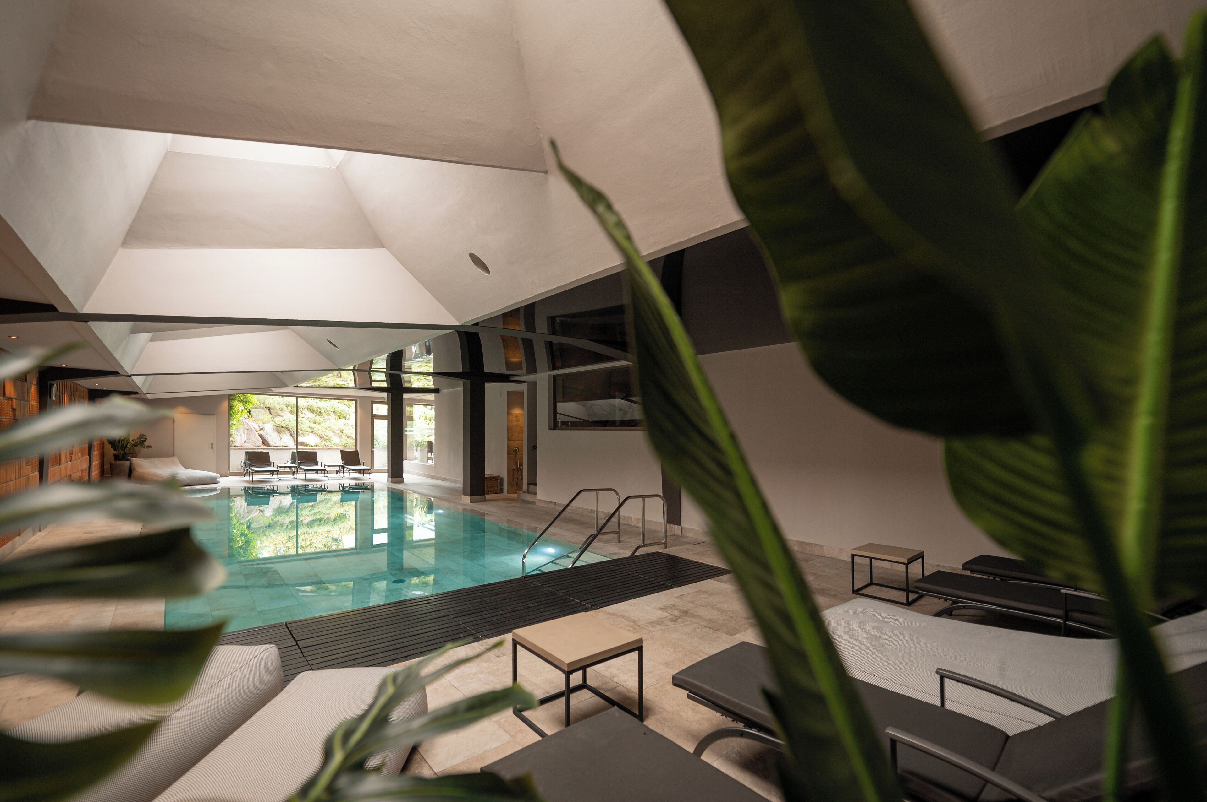 Una piscina interior con sillones de descanso y vistas al exterior.
