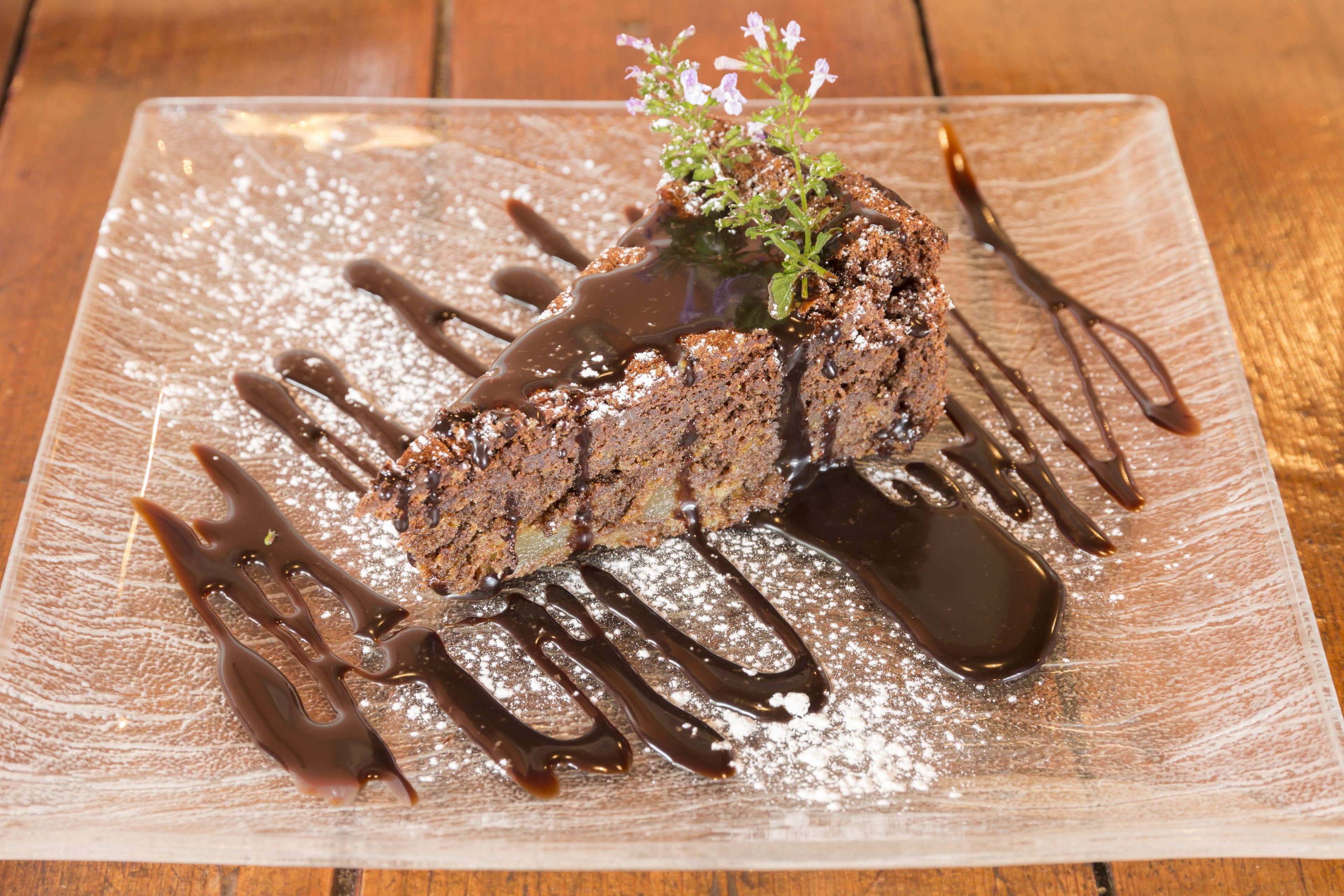 A dessert on a rectangular plate with chocolate sauce and powdered sugar.
