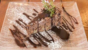 A dessert on a rectangular plate with chocolate sauce and powdered sugar.