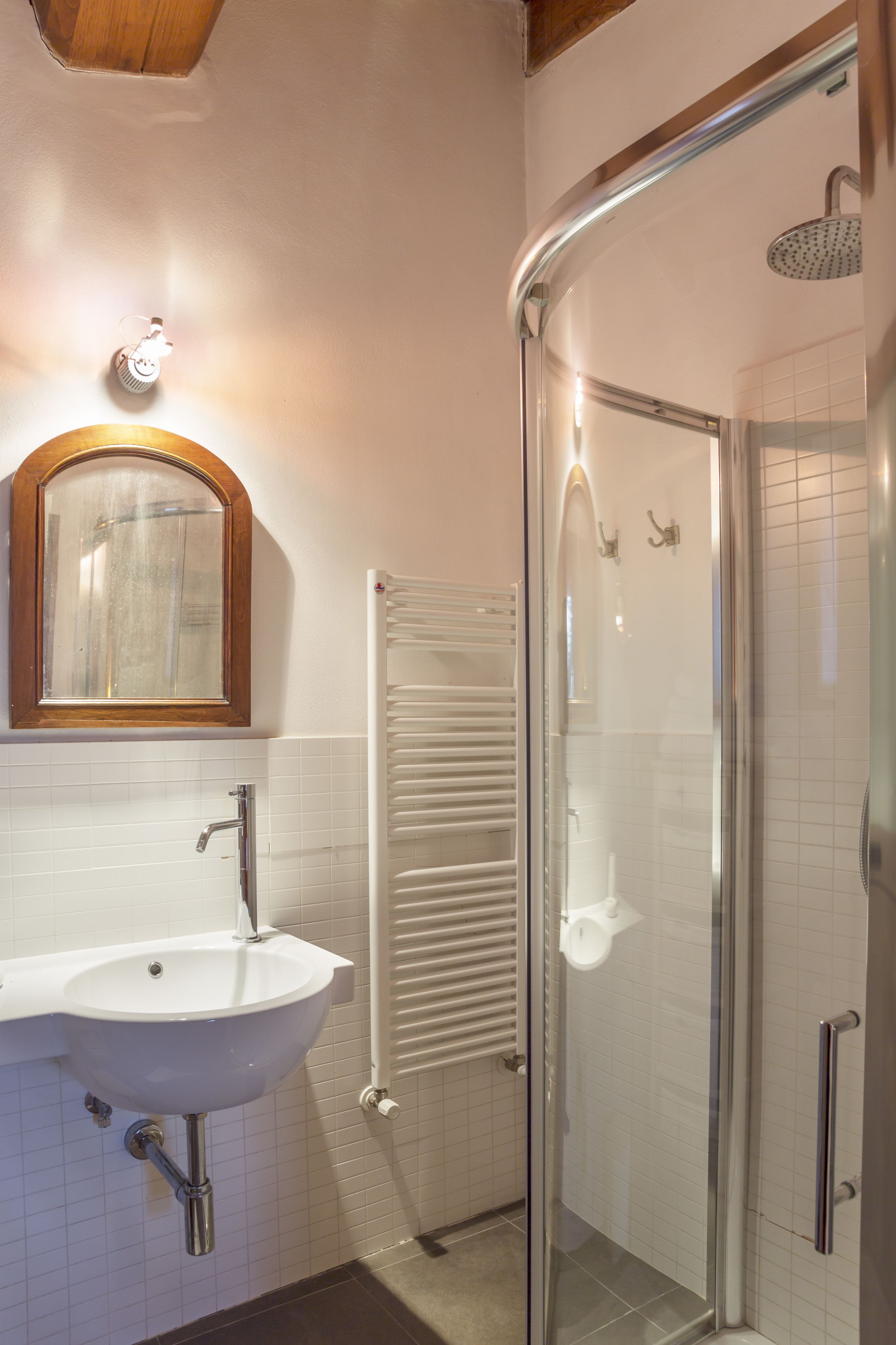 A bathroom with a white sink, a mirror, a glass shower enclosure, and a towel rack.