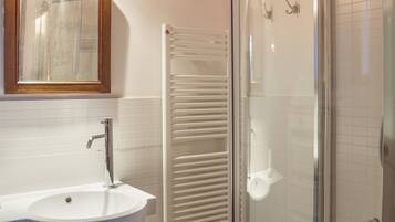 A bathroom with a white sink, a mirror, a glass shower enclosure, and a towel rack.